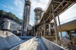 © Starlight - Massive hoppers pour cement into mixers. The plant hums with steady activity.