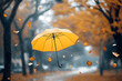 © Nasim Reza - a yellow umbrella flying in the air, surrounded by falling leaves, with a blurry background of a park with trees and foggy weather