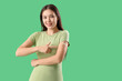 © Pixel-Shot - Beautiful young woman pointing at applied medical patch on her arm against green background