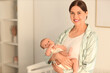 © Pixel-Shot - Mother holding her little baby in bedroom