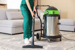 © New Africa - Professional cleaning service worker vacuuming rug indoors, closeup