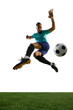 © Lustre Art Group  - Side view of football player in blue uniform airborne, preparing to strike ball with intense focus and athleticism on green field. Concept of sportsmanship, tournament, professional performance