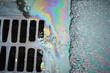 © AleksFil - Colorful Oil Sheen Reflecting in Water Near a Storm Drain on a Rainy Day in an Urban Environment