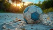 © Irma - Worn soccer ball on sandy beach at sunset.