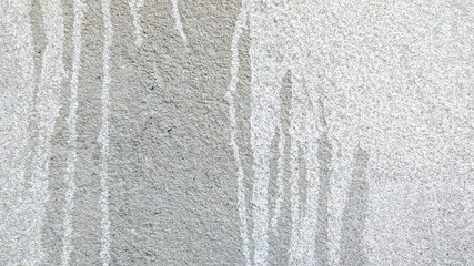 Poster - White paint streaks flowing down a rough textured gray concrete wall, forming a visually striking abstract design, perfect for backgrounds and textures