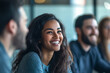 © Tahsin - A young woman smiling during a meeting with coworkers in a bright office setting with natural light