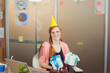 © WavebreakMediaMicro - Smiling woman in party hat holding gifts at office birthday celebration