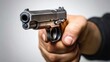 © Lakshmi - Close-up of a hand holding a handgun pointed straight ahead against a gray background
