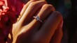 © budi - Close-up of a woman's hand showcasing an elegant engagement ring among vibrant pink flowers in a sunlit garden