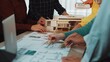 © InfiniteFlow - A vibrant scene depicting a diverse group of architects collaborating on a design project, using blueprints and a physical model during an engaging planning session. SACTR