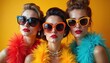 © Pete - Glamorous fashion trio in sunglasses, colorful feather boas against orange background. Elegant women with bright makeup, jewelry posing. Stylish girls show vivid, luxury, fancy, modern apparel.
