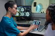 © pressmaster - Medical professional explaining brain scans on a tablet to a patient showing detailed images surrounded by high-tech equipment in a clinical setting