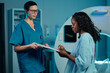 © pressmaster - Healthcare professionals in medical facility reviewing patient charts near advanced imaging equipment, creating treatment strategy for improved patient care and outcomes