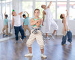 © JackF - Expressive preteen girl honing hip hop dance moves in sunlit choreographic studio setting during training with group of children and teacher