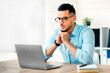 © Prostock-studio - A young Middle Eastern businessman is deeply engaged while working on his laptop in a contemporary office. He appears thoughtful, contemplating important decisions related to his career.