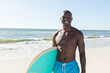 © wavebreak3 - Smiling man holding surfboard on sunny beach, enjoying summer day, copy space