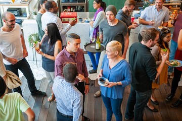Aufkleber - Diverse group socializing at a casual gathering. Men and women of various ethnicities enjoying drinks and conversation in a lively atmosphere. Diverse people mingle at social gathering.