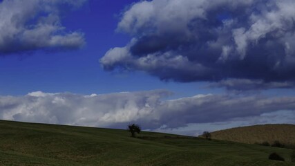 Wall Mural - Time-lapse footage of the white clouds rolling in the clear blue sky over green hills during daytime