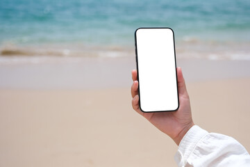 Wall Mural - mockup image of a woman holding mobile phone with blank desktop screen by the sea