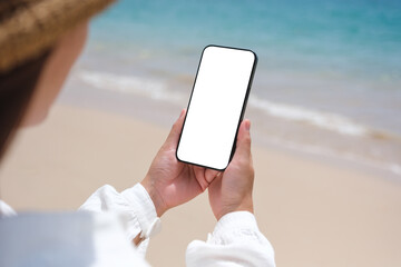 Wall Mural - mockup image of a woman holding mobile phone with blank desktop screen by the sea