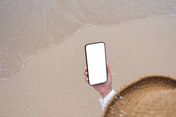 Wall Mural - top view mockup image of a woman holding mobile phone with blank desktop screen by the sea