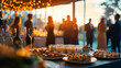 © AspctStyle - Elegant buffet table with gourmet appetizers and wine glasses at a sunset outdoor event. People socializing at a formal gathering