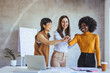 © Dragana Gordic - Three Professional Women Celebrating Teamwork and Success in a Modern Office Setting
