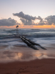 Wall Mural - morning view of stormwater pipe with waves at manly beach, sydney, australia.