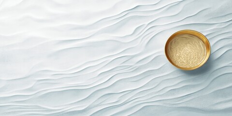 Poster - A golden bowl holds a liquid and is positioned on a wavy, light-colored surface that creates a calming aesthetic. Soft lighting enhances the textures