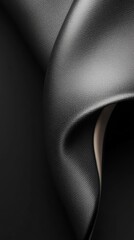Poster - A close-up view of black fabric gracefully draping, revealing a smooth texture illuminated by soft lighting that enhances its depth and elegance