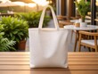 © Tianci - A white tote bag sits on a wooden table, with a blurred outdoor patio and potted plants in the background.
