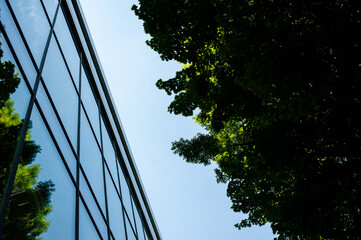 futuristic city building with glass walls reflecting trees and sky, emphasizing harmony between arch