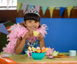 © wavebreak3 - Young girl in princess costume enjoying tea party with colorful treats, copy space