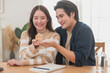 © surachetkhamsuk - Happy Asian family young couple in love hand holding model house for saving money to buy real estate for new home