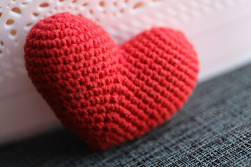Poster - A small red knitted heart sits on a table, perfect for decoration or gift giving.
