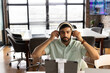 © Wavebreak Media - Man in office wearing headphones, focusing on video call with tablet