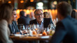 © Pranjul - Group of executives engaged in a lively discussion at a networking lunch event, with warm ambient lighting.