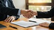 © Qbertstudio - Caucasian man and Asian woman shake hands in an office during a business agreement over contracts Themes of collaboration and professional success