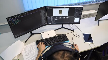 a Russian hacker programmer writes program code working on two monitors