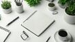 © sadewotito - Blank spiral notebook on white desk with coffee, pencils, plants, and glasses.