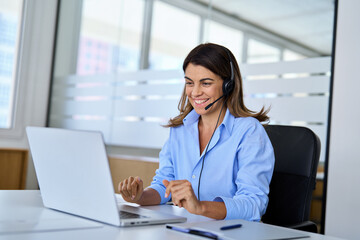 Fototapete - Busy happy middle aged female support service operator talking to customer sitting at desk. Smiling mature woman professional call contact center agent in headset working in office using laptop.