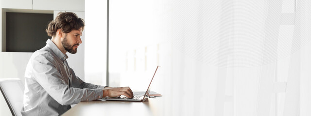 Poster - Side view of handsome mature businessman working at office, using laptop computer, sitting at desk, copy space. Man entrepreneur typing on pc keyboard, checking email, developing business strategy