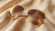 © sadewotito - Gold aviator sunglasses on beige silk fabric.