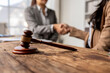 © Apichat - A woman shakes hands with another woman in a courtroom