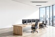 © peshkova - Modern office interior with wooden desk, ergonomic chairs, and multiple monitors in a high-rise building with city skyline view through large windows.