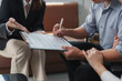 © Phimwilai - Businessman signing important legal document on clipboard while businesswoman explaining terms and conditions of contract during business meeting