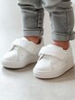 © Alla - Close-up shot of a person's footwear, featuring white shoes