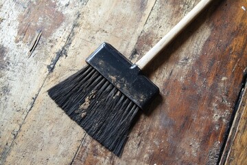 Poster - A single black brush sitting on top of a wooden floor, great for adding context to still life photography or as a prop in minimalist interior designs