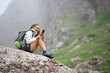 © Antonioguillem - Happy hiker using smart phone sitting on a rock in nature