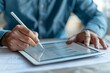 © Vera - Close-up of a businessman completing an online survey on a tablet in an office.